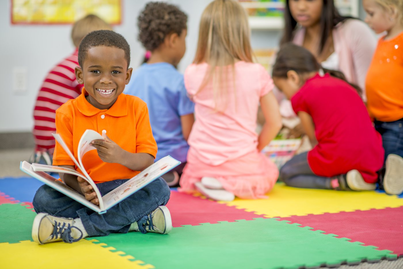 A young student reading a decodable book with his class
